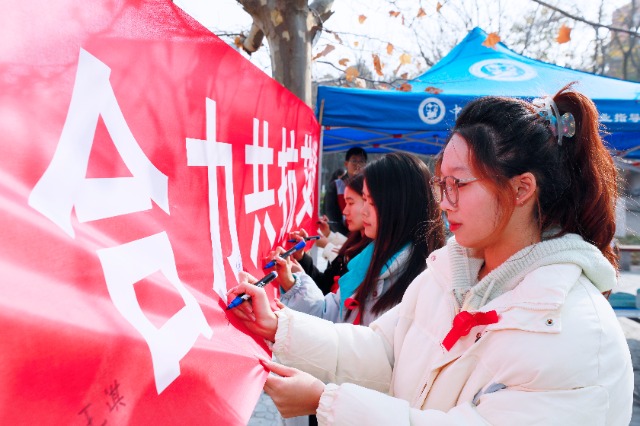 20231127中國石油大學(xué)（華東）青年學(xué)子在合力共抗艾滋的條幅上簽字，表達(dá)抗擊艾滋病的決心和信心  .jpg